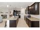 Stylish kitchen featuring dark cabinetry, granite countertops, a large island, and stainless steel appliances at 8090 Penrose Pl, Wildwood, FL 34785