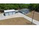 Aerial view of a gray home with attached carport and detached three-car garage with concrete driveway at 9885 Se 144Th St, Summerfield, FL 34491