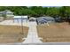 Aerial view of a gray home with a long driveway leading to a detached three-car garage at 9885 Se 144Th St, Summerfield, FL 34491