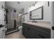 Modern bathroom featuring a gray vanity, new lighting, and a glass-enclosed shower with gray tiling at 9885 Se 144Th St, Summerfield, FL 34491