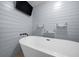 Bathroom with a standalone tub, plank walls, modern fixtures, and floating shelves, offering a clean and stylish design at 9885 Se 144Th St, Summerfield, FL 34491