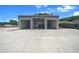 Exterior of a modern metal building with three bays, an automotive lift, and concrete driveway, set in a beautiful yard at 9885 Se 144Th St, Summerfield, FL 34491
