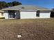 Home's backyard featuring sliding glass door, gray roof, window, and sparse lawn at 11120 Sw 71St Terrace Rd, Ocala, FL 34481