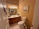 Half bathroom with a vanity, toilet, and decorative elements against warm, neutral tones at 12453 Se 93Rd Court Rd, Summerfield, FL 34491