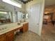 Bright bathroom featuring double sinks, vanity area, neutral tile floor and view into main bedroom at 12453 Se 93Rd Court Rd, Summerfield, FL 34491