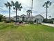 Beautiful single-story home featuring a well-manicured lawn, lush landscaping, and stately palm trees at 12453 Se 93Rd Court Rd, Summerfield, FL 34491