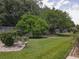 Serene backyard featuring a lush lawn, mature trees, a wooden fence, and thoughtful landscaping at 13196 Se 86Th Cir, Summerfield, FL 34491