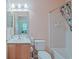 Bright bathroom featuring a single sink vanity, mirror, toilet, and a shower with a floral patterned curtain at 13196 Se 86Th Cir, Summerfield, FL 34491