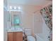Bright bathroom featuring a single sink vanity, mirror, toilet, and a shower with a floral patterned curtain at 13196 Se 86Th Cir, Summerfield, FL 34491