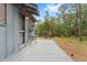 View of a home's outdoor deck with seating area surrounded by a lush green backyard and trees at 14620 Se 47Th Loop, Ocklawaha, FL 32179