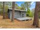 Exterior view of a cozy house with wood siding and a deck, nestled among tall pine trees at 14620 Se 47Th Loop, Ocklawaha, FL 32179