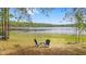 Scenic view of a lake from the backyard, featuring two chairs and a small table for enjoying the outdoors at 14620 Se 47Th Loop, Ocklawaha, FL 32179