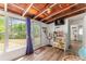 Sunroom featuring a view of nature, a bookshelf, a fan, and access to the hallway with wood grain flooring at 14620 Se 47Th Loop, Ocklawaha, FL 32179