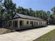 Side angle of the home featuring a large porch, long driveway, and lush green trees at 18890 Sw 60Th St, Dunnellon, FL 34432