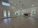 Spacious living room boasts a fireplace, wood-look tile floors, large windows, and a high ceiling with a ceiling fan at 18890 Sw 60Th St, Dunnellon, FL 34432
