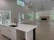 Bright, open-concept living room with wood-look floors, an island bar, fireplace, and double doors to the backyard at 18890 Sw 60Th St, Dunnellon, FL 34432