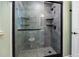 Modern bathroom shower with gray tile, glass door, rainfall shower head, and mosaic-tiled floor at 19300 Sw 60Th St, Dunnellon, FL 34432