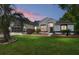 Charming single-story home features an attached garage, manicured lawn, and mature landscaping at dusk at 19395 Sw 100Th Loop, Dunnellon, FL 34432
