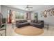 Cozy living room with tile floors, area rug, large sofa, and bright windows with decorative drapes at 19395 Sw 100Th Loop, Dunnellon, FL 34432