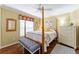 Sunlit bedroom features a four-poster bed, wood floors, and neutral walls, creating a serene and inviting space at 2008 Palo Alto Ave, The Villages, FL 32159
