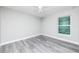 Bright bedroom featuring a ceiling fan, gray wood-look floors, and a large window allowing natural light at 2376 Se 40Th Street Road, Ocala, FL 34480