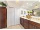 Bathroom with double vanity, dark wood cabinets, and adjacent closet with sliding doors at 4404 Ne 4Th St, Ocala, FL 34470
