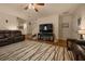 Bright living room with hardwood floors, leather sofa, large television, and staircase visible in background at 5128 Grassy Knoll Dr, Tavares, FL 32778
