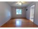 Bright, empty bedroom featuring wood-look floors, ceiling fan, window, and en suite bathroom access at 6150 Sw 103Rd Loop, Ocala, FL 34476