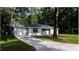 Inviting single-story home featuring a long driveway and attached garage, nestled in a wooded area at 6432 Nw 64Th Ter, Ocala, FL 34482