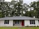 Charming single-story home with gray and white siding, a red front door, and manicured landscaping at 6432 Nw 64Th Ter, Ocala, FL 34482