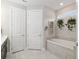 Bright bathroom with a soaking tub, white cabinets, tile surround, and decorative greenery at 6816 Sw 95Th Cir, Ocala, FL 34481