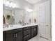 Modern bathroom featuring dual sinks, dark cabinets, white countertop, and decorative accents at 6816 Sw 95Th Cir, Ocala, FL 34481