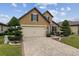 Two-story home featuring a brick driveway, manicured lawn, and stone accents on the facade at 6816 Sw 95Th Cir, Ocala, FL 34481