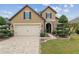 Charming two-story home featuring a brick driveway, manicured lawn, and stone accents on the facade at 6816 Sw 95Th Cir, Ocala, FL 34481