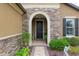 The front door is framed by a stone archway and flanked by lush landscaping at 6816 Sw 95Th Cir, Ocala, FL 34481