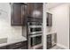 Kitchen with built-in stainless steel ovens, wine rack, beverage cooler, granite countertops, and dark cabinets at 6816 Sw 95Th Cir, Ocala, FL 34481