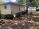 Fenced backyard featuring landscaping, a white house, and an open gate at 9896 Sw 61St Ct, Ocala, FL 34476