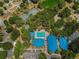 Breathtaking aerial view of tennis courts and community pool surrounded by vibrant green landscape and mature trees at 10824 Sw 90Th Ter, Ocala, FL 34481
