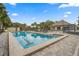 A long rectangular community pool with steps, seating area, and palm trees with building on a sunny day at 10824 Sw 90Th Ter, Ocala, FL 34481