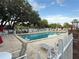 Community pool surrounded by lounge chairs, mature trees, and a well-maintained fence for privacy at 10980 Sw 63Rd Ave, Ocala, FL 34476