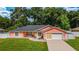 Charming coral home featuring a well-manicured lawn, attached garage, and stone accents at 1109 Ne 22Nd Ave, Ocala, FL 34470