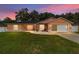 Sunset view of a single-story home boasting a well-kept lawn and an attached garage at 1109 Ne 22Nd Ave, Ocala, FL 34470