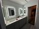 Bathroom with dual sinks, LED mirrors, gray countertops, and white-paneled walls at 14 Se 62Nd Ter, Ocala, FL 34471