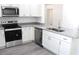 Modern kitchen featuring granite countertops, stainless steel appliances, white cabinets, and wood-look floors at 20 Malauka Pass Crse, Ocklawaha, FL 32179