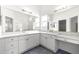 Bathroom featuring dual sinks, white cabinets, and mirrors at 2087 Bonneau Ln, The Villages, FL 32162