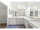 Bathroom featuring dual sinks, white cabinets, and large mirrors at 2087 Bonneau Ln, The Villages, FL 32162