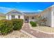 Quaint single-Gathering home with a brick walkway leading to the front door, surrounded by lush greenery and landscaping at 2087 Bonneau Ln, The Villages, FL 32162
