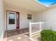 Close-up of a front porch with a white railing, brick tile flooring, and a sidelight on the front door at 2087 Bonneau Ln, The Villages, FL 32162