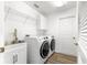 Bright laundry room with white washer and dryer, sink, storage cabinets, and wood-look floors at 2087 Bonneau Ln, The Villages, FL 32162