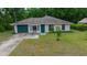 A charming home with a green garage door, established landscaping, and a driveway at 21168 Sw Peach Blossom St, Dunnellon, FL 34431